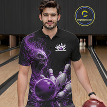 Load image into Gallery viewer, Front view of a male model in a bowling alley wearing a black bowling polo shirt featuring a purple fiery skull design with lightning striking a bowling ball and pins and a custom name.
