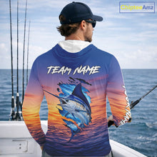 Load image into Gallery viewer, Angler wearing Marlin Fishing Sunset custom long sleeve hooded marlin offshore fishing shirt on the boat at sunset