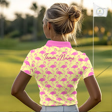 Load image into Gallery viewer, Woman wearing a yellow polo shirt with pink flamingo pattern and 'Team Name' text on the back, standing on a golf course.
